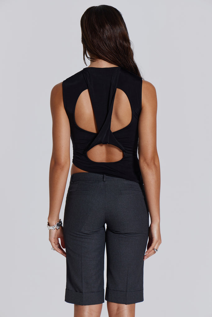 Female model wearing a black high neck top with a twisted back, asymmetric hemline detail and pleated side seam. Paired with charcoal grey tailored shorts. 