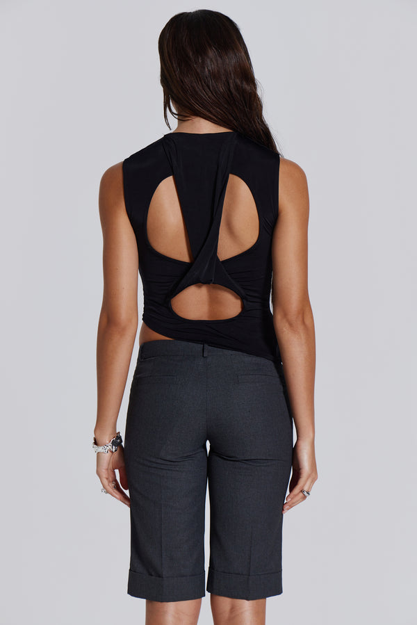 Female model wearing a black high neck top with a twisted back, asymmetric hemline detail and pleated side seam. Paired with charcoal grey tailored shorts. 